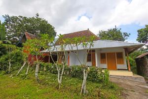 una pequeña casa con árboles delante de ella en SPOT ON 92567 Jati Homestay, en Lombok