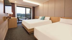 a hotel room with two beds and a television at Chuncheon Eston Hotel in Chuncheon