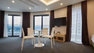 um quarto de hotel com uma mesa, cadeiras e janelas em Chuncheon Eston Hotel em Chuncheon