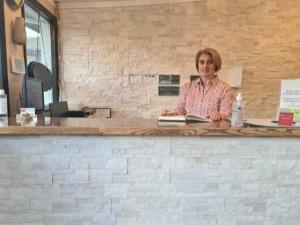 a woman sitting at a counter with a book at Sundowner Motel in Cache Creek