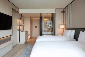 a hotel room with two beds and a television at dusitD2 Samyan Bangkok in Bangkok