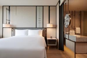 a bedroom with a large white bed and a bathroom at dusitD2 Samyan Bangkok in Bangkok