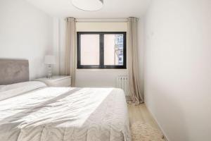 um quarto branco com uma cama e uma janela em Piso en Ribeira, primera línea. em Ribeira