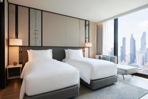 a bedroom with two beds and a large window at dusitD2 Samyan Bangkok in Bangkok