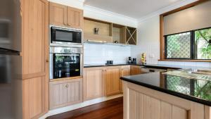 eine große Küche mit Holzschränken und einer Mikrowelle in der Unterkunft 5 The Point Apartments Port Douglas in Port Douglas