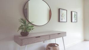 a mirror on a wall with a table and a plant at Papaya Port Douglas in Port Douglas
