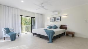 a bedroom with a bed and a chair and a window at Papaya Port Douglas in Port Douglas