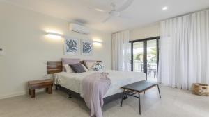 a bedroom with a large bed and a balcony at Papaya Port Douglas in Port Douglas