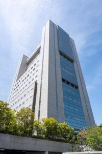 een hoog wit gebouw met bomen ervoor bij Toshi Center Hotel in Tokyo