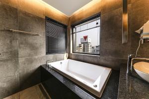 baño con bañera, lavabo y ventana en Heritage31 Hotel, en Seúl
