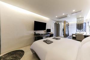 1 dormitorio con 1 cama blanca y TV de pantalla plana en Heritage31 Hotel, en Seúl