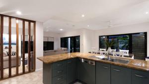 a kitchen with a sink and a living room at Catalina Port Douglas in Port Douglas +7 photos