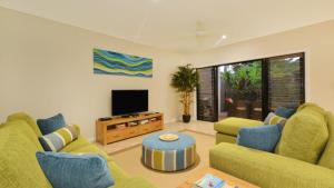 sala de estar con 2 sofás y TV en Sanctuary At Thornton's Port Douglas, en Port Douglas