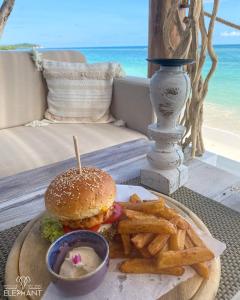 een hamburger en frietjes op een tafel met het strand bij Elephant Beach Club & Resort Samui in Chaweng Beach