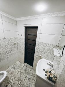 ein Bad mit einem Waschbecken, einem WC und einer Tür in der Unterkunft Однокімнатна дизайнерська квартира поруч з термальними водами in Berehowe