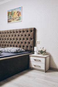 ein Bett mit einem getufteten Kopfteil neben einem Nachttisch in der Unterkunft Однокімнатна дизайнерська квартира поруч з термальними водами in Berehowe
