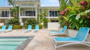 uma fila de cadeiras e uma piscina num resort em 9 Plantation House Port Douglas em Port Douglas