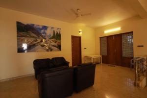 a living room with two chairs and a painting on the wall at royal stay in Madurai