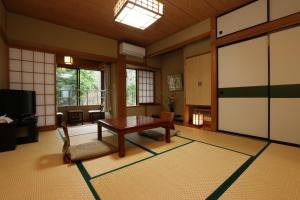 a living room with a table and a tv at Teiensaryo Yamanakako in Yamanakako