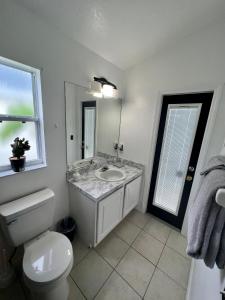 a bathroom with a sink and a toilet and a window at Grand Superior 4BR Pool House near Disney Parks in Davenport