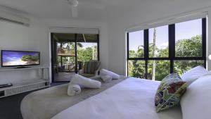 biała sypialnia z dużym łóżkiem i telewizorem w obiekcie 6 The Point Apartments w mieście Port Douglas