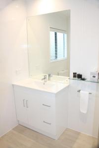 a white bathroom with a sink and a mirror at Camelot On Ulster in Hamilton