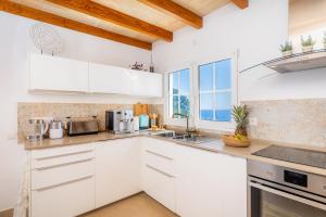 eine Küche mit weißen Schränken und einem großen Fenster in der Unterkunft Villa Seaview in Canyamel