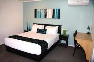 a bedroom with a bed and a desk at Camelot On Ulster in Hamilton
