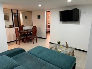 ein Wohnzimmer mit einem blauen Sofa und einem Tisch in der Unterkunft Encantador apartamento cerca al aeropuerto in Bogotá