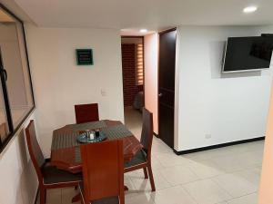 ein Esszimmer mit einem Tisch, Stühlen und einem TV in der Unterkunft Encantador apartamento cerca al aeropuerto in Bogotá