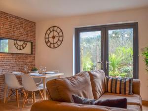 ein Wohnzimmer mit einem Sofa und einem Tisch in der Unterkunft River Lodge Annexe in Rhondda