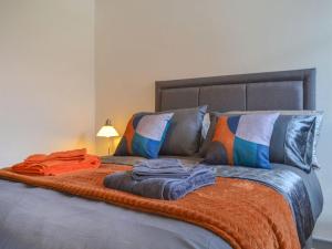 a bed with an orange blanket and pillows on it at River Lodge Annexe in Rhondda