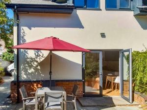 una sombrilla roja sentada junto a una mesa y sillas en River Lodge Annexe, en Rhondda