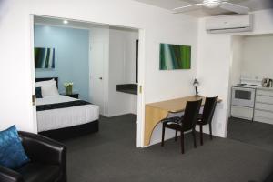 a hotel room with a bed and a table and chairs at Camelot On Ulster in Hamilton