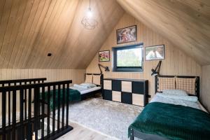 a attic room with two beds and a window at Hytte Na Wyspie -,,Roztoczańskie Morze'' in Kulików