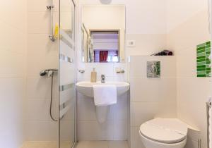 a white bathroom with a sink and a toilet at Panoramic Center Rooms in Braşov