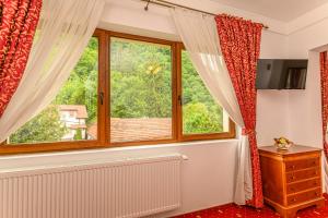 Habitación con ventana con cortinas rojas y radiador en Panoramic Center Rooms en Braşov