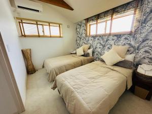 a bedroom with two beds and a window at ResortHouse-KAPUKA in Chatan