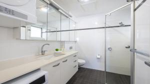 a bathroom with a shower and a sink and a toilet at Waves On Main 20 in Yamba