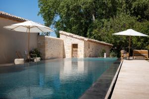a swimming pool with two umbrellas next to a house at Domaine de Panery in Pouzilhac