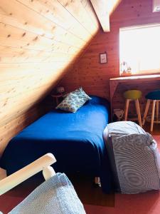 1 dormitorio con 1 cama azul en una cabaña de madera en 1組限定ドッグフレンドリー&イギリス料理 Laughing dogs villa, en Takashima