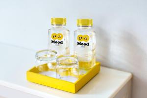 two bottles and two glasses on a yellow tray at Mood Hotel Pattaya in Pattaya Central