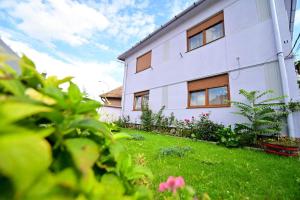 een wit huis met een tuin met groen gras en bloemen bij FLH - Natalia 1 - Turnisor in Sibiu
