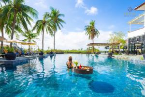 Eine Frau im Wasser in einem Resortpool in der Unterkunft Hoi An Beach Resort in Hoi An