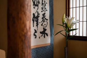 Third&Place Kyoto_ShijoOmiya/四条大宮 في كيوتو: مزهرية فيها ورد بجانب نافذة