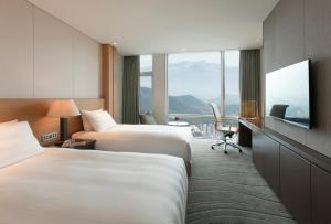 a hotel room with two beds and a flat screen tv at LOTTE City Hotel Jeju in Jeju