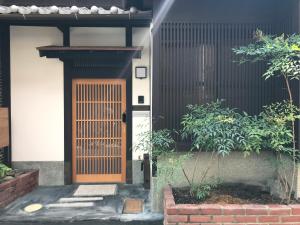Third&Place Kyoto_ShijoOmiya/四条大宮 في كيوتو: منزل فيه باب خشبي وبعض النباتات