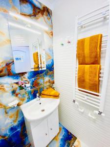 La salle de bains est pourvue d'un lavabo blanc et d'une serviette jaune. dans l'établissement IANIS Rooms, à Mangalia