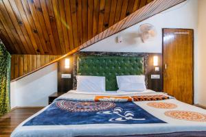 a bedroom with a large bed with a green headboard at MHA hotels MOORANG mall manali in Manāli