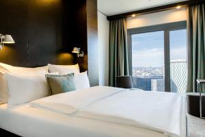 Un dormitorio con una gran cama blanca y una ventana en Motel One Wien-Hauptbahnhof en Viena